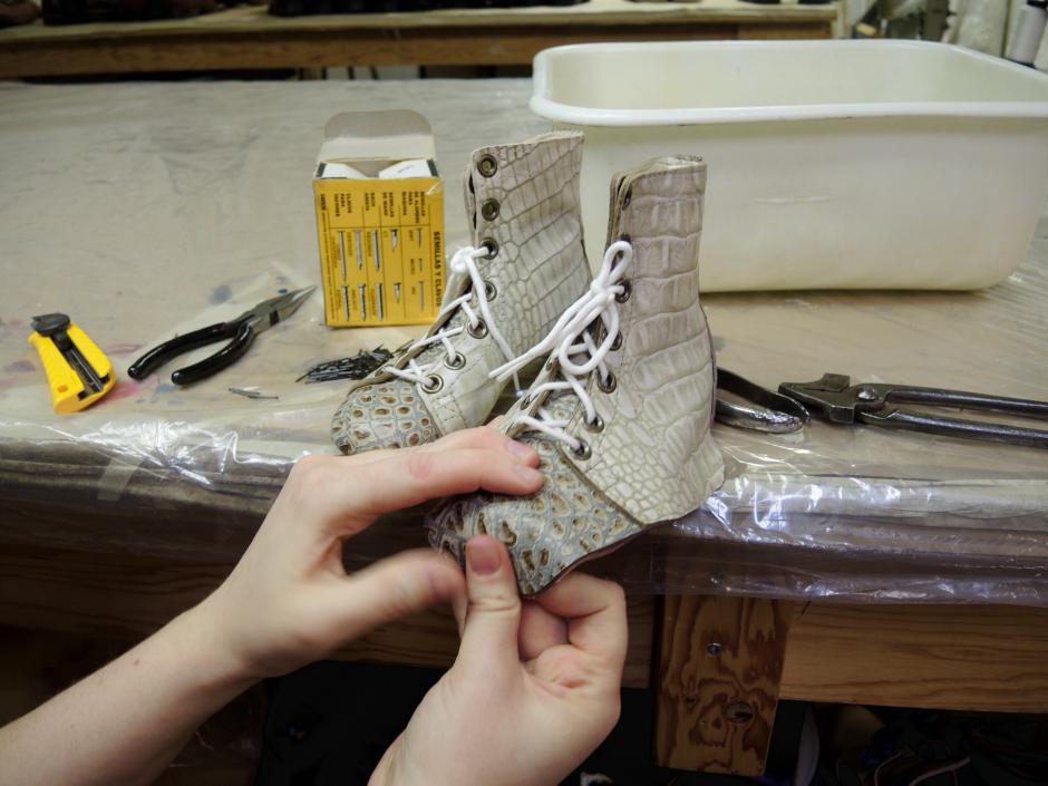 One completed boot sits on the table, the second one ready to be lasted