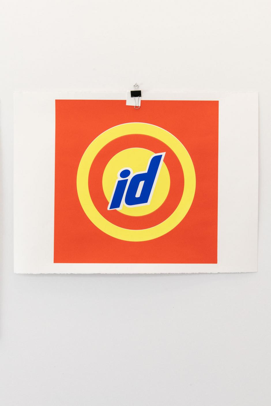 Single artwork featuring the letters 'id' overtop yellow circles on a orange background hanging on the wall of Dana's studio at Banff Centre.