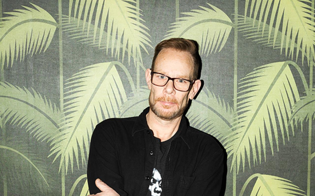 DJ Rob Faust standing against palm tree pattern wall paper