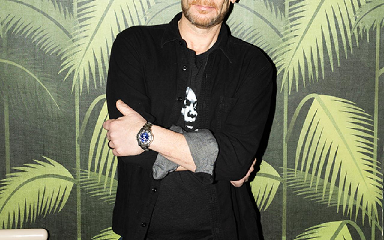 DJ Rob Faust standing against palm tree pattern wall paper