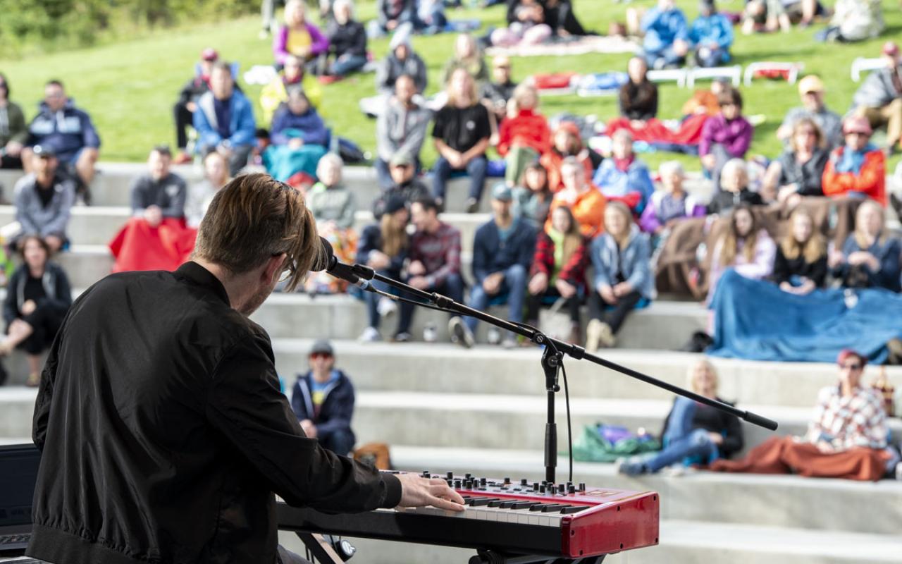 Outdoor setting with a musician on stage in front of a crowd