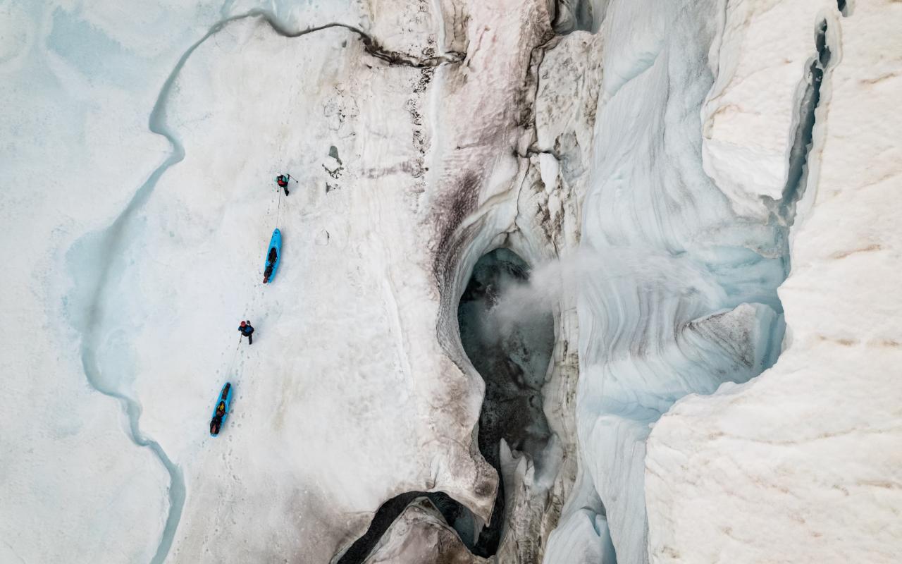 Two people pulling kayaks on a glacier 