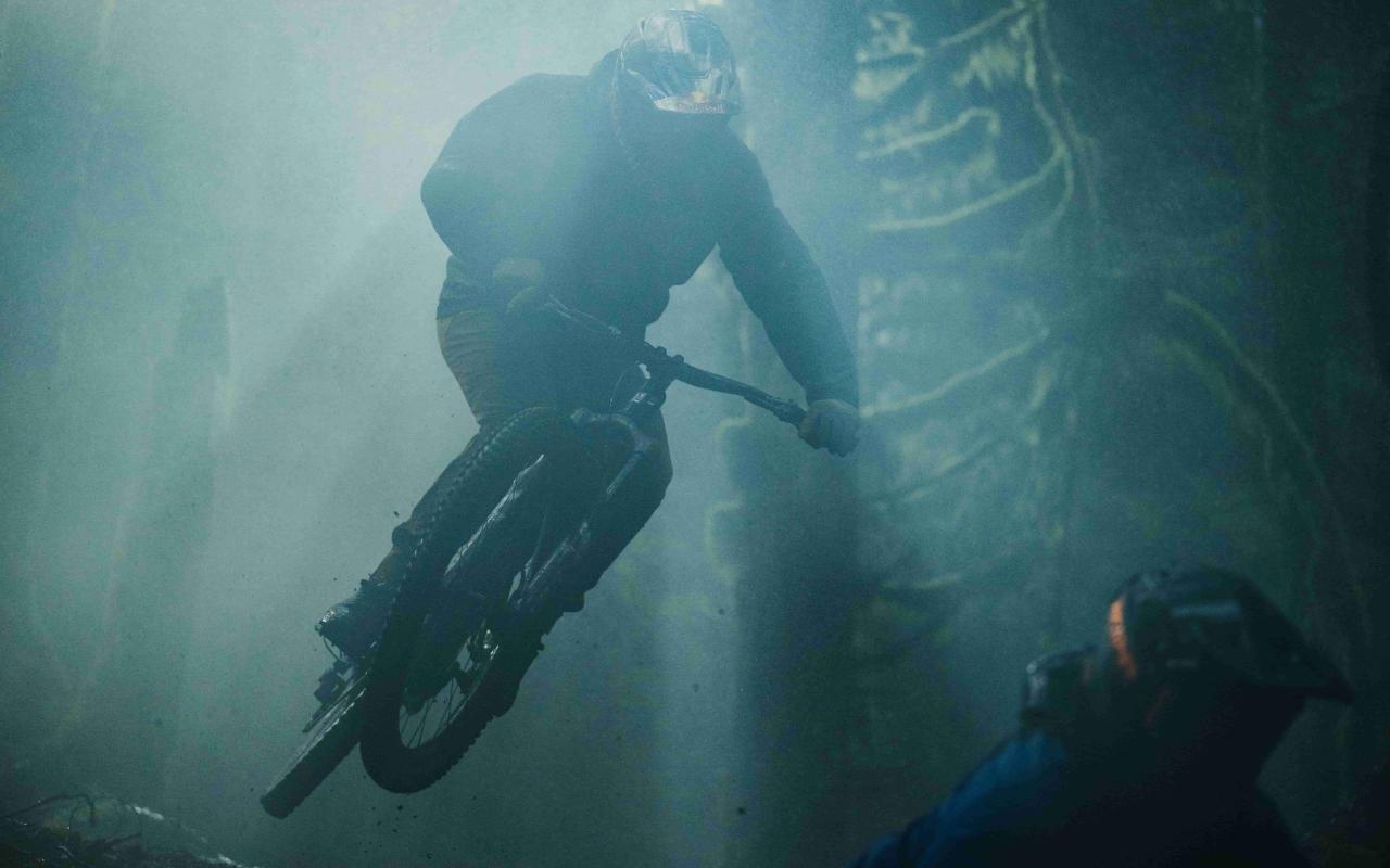 Mountain biker jumping in a dense forest