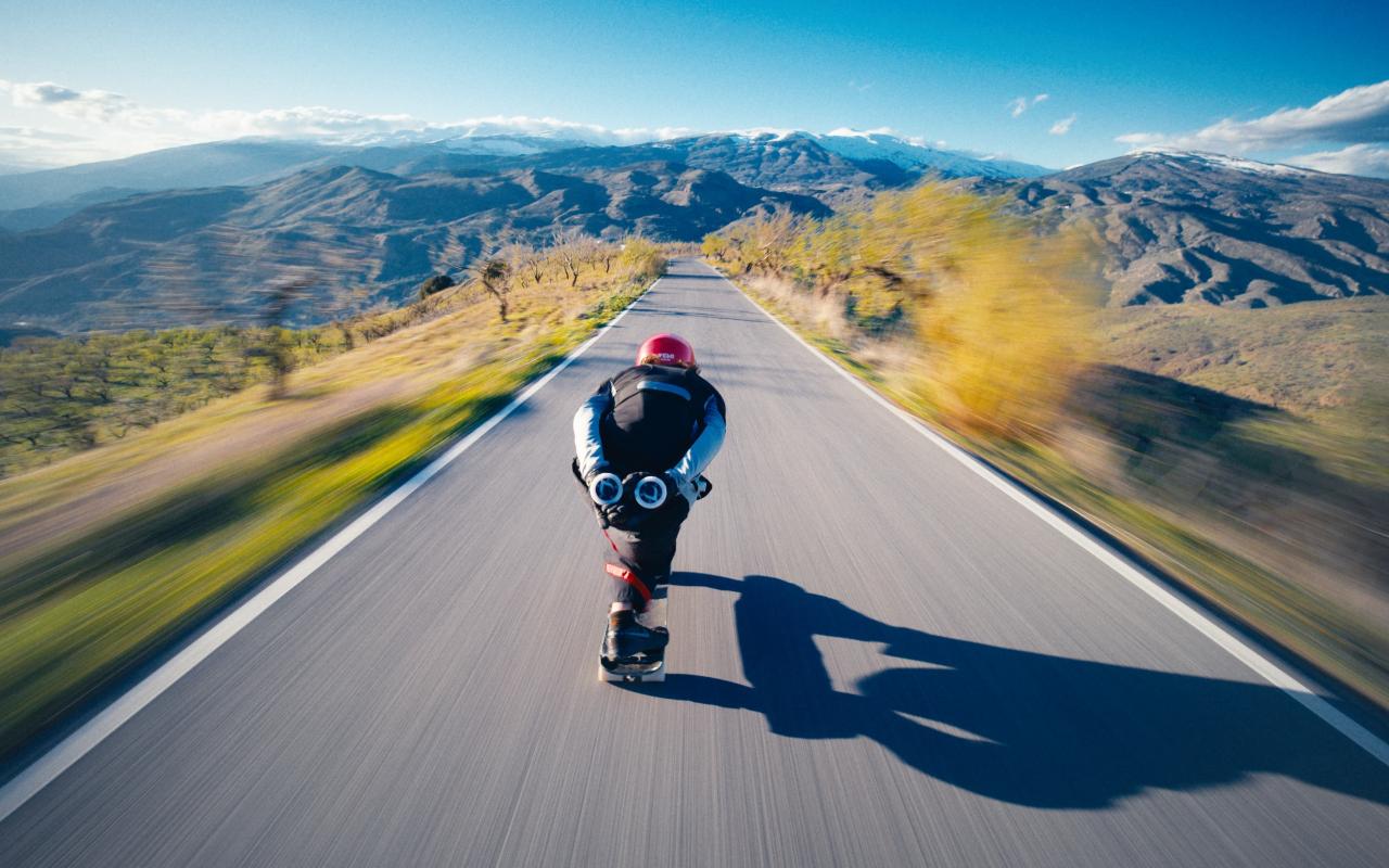 Man on a skate taking speed in a road 