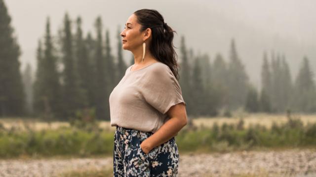 Photo of a female artist overlooking a nature filled landscape. 