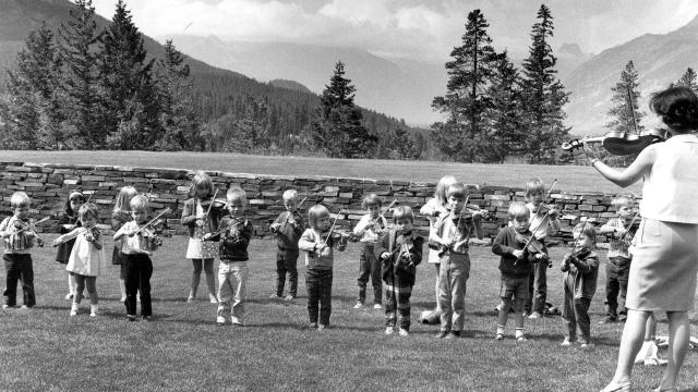 Oike-Wong is pictured here teaching a violin lesson to students on the lawn in front of our Donald Cameron Hall, overlooking the Bourgeau Range.