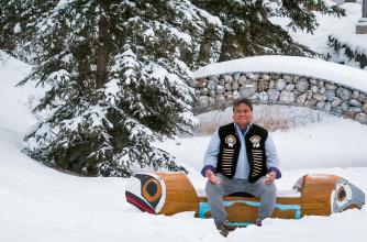 Simon Ross sits on a bench in the snow on the Banff Centre campus
