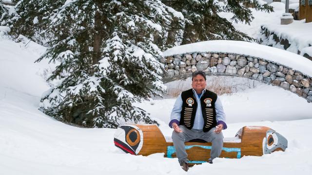 Simon Ross sits on a bench in the snow on the Banff Centre campus