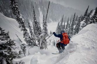 A skier is dropping off a cliff into deep powder 