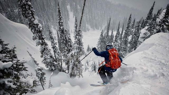 A skier is dropping off a cliff into deep powder 