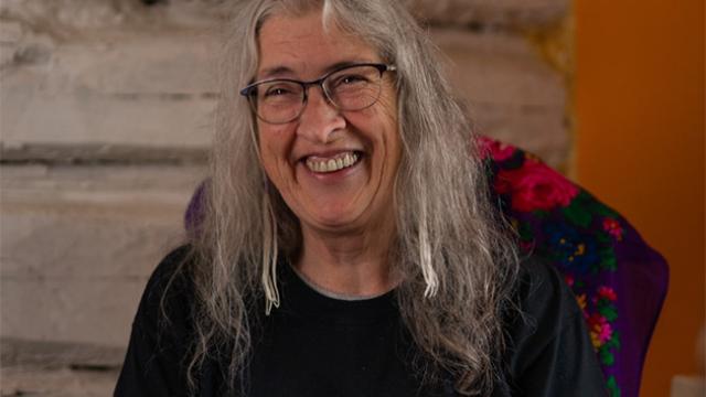 Marjorie Beaucage is seated on a chair and smiling at the camera