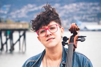 Cris Derksen on a beach seated in front of the pier with her Cello, to perform at Banff Centre 2018.