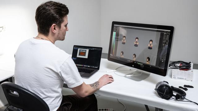 A person is seated at a desk while viewing digital animations on a computer screen