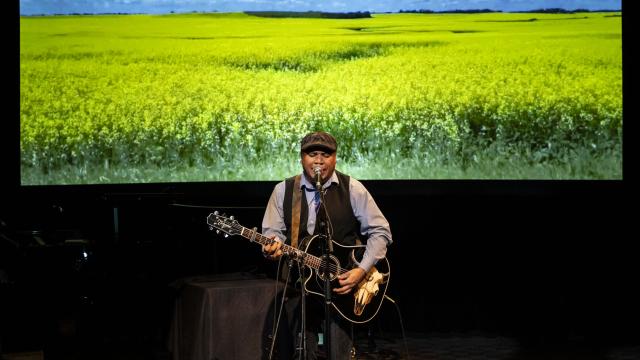 Dale Mac playing a guitar on stage