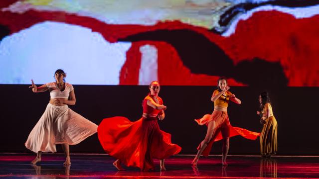 Four dancers performing in costume on stage.