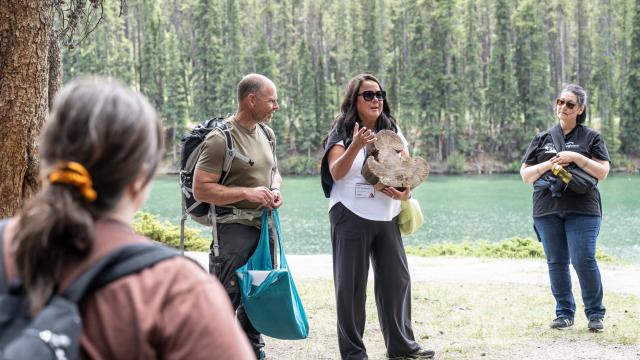 A group of people are standing outdoors listening to an instructor