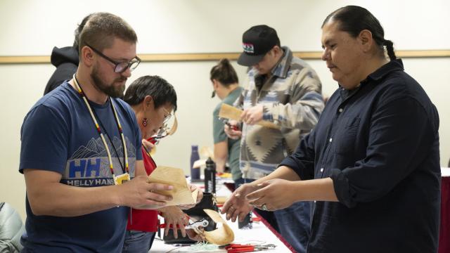 An instructor is demonstrating an activity to a participant standing in a classroom