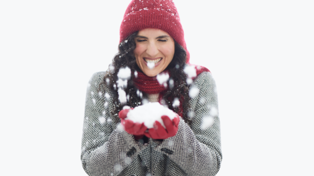 happy smiling Woman with winter red har and gloves holding ball of fresh snow between her hands 