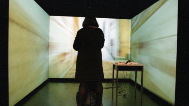 Woman stands before three wall sized screens