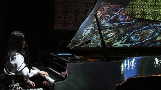 Pianist in a dark stage with lights projection 
