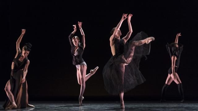 Four dancers in black costume on stage