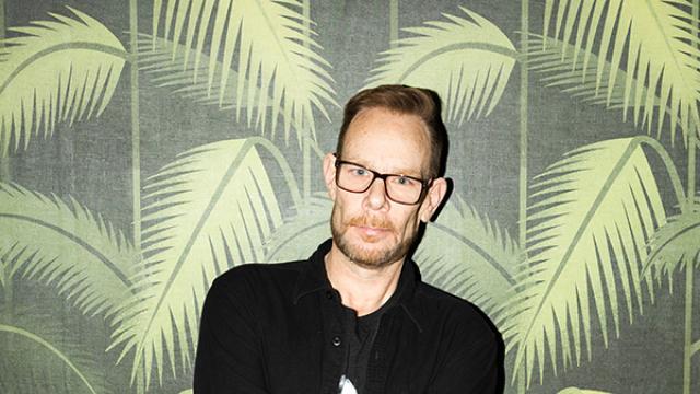 DJ Rob Faust standing against palm tree pattern wall paper