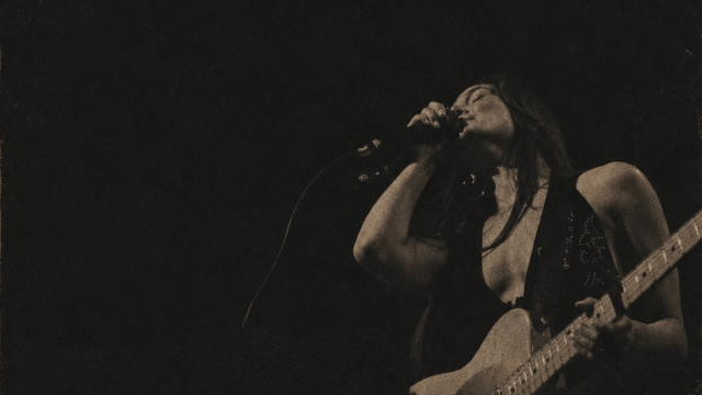 black blackground with overlay of a woman singing and playing guitar