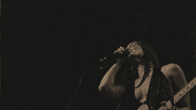 black blackground with overlay of a woman singing and playing guitar