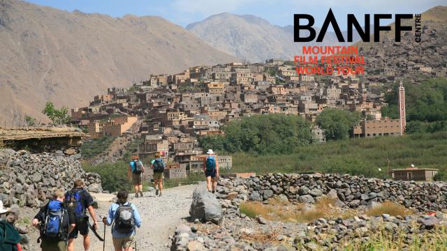 Group of hikers approaching settlement surrounded by mountains