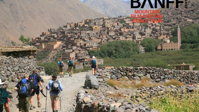 Group of hikers approaching settlement surrounded by mountains