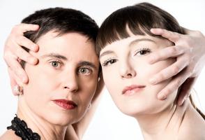 A headshot of Luciane and Katelyn with their hands on the face looking at us. 