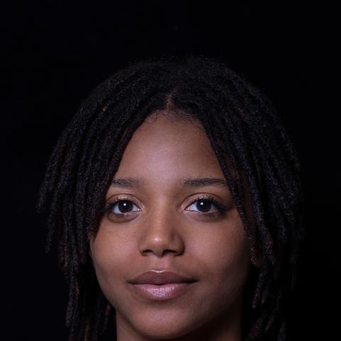 straight on portrait of woman smiling lightly at camera with dark background