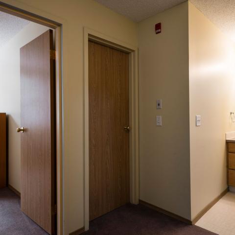 Two wooden bedroom doors in a well lit apartment. 
