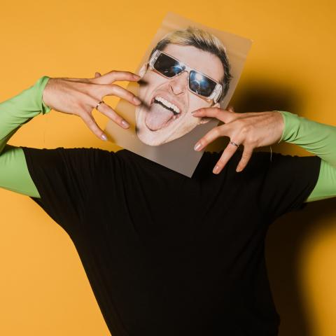 Guy holding a picture of a head on his head with a big smile