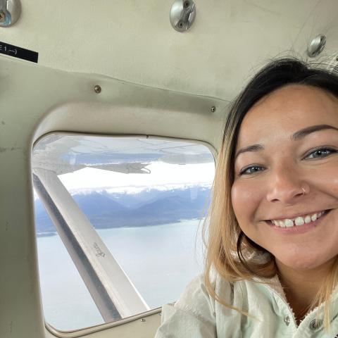 Women smiling in an airplane flying over the ocean 