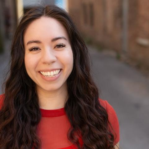 Women smiling with long and curly hair wearing a red t-shirt