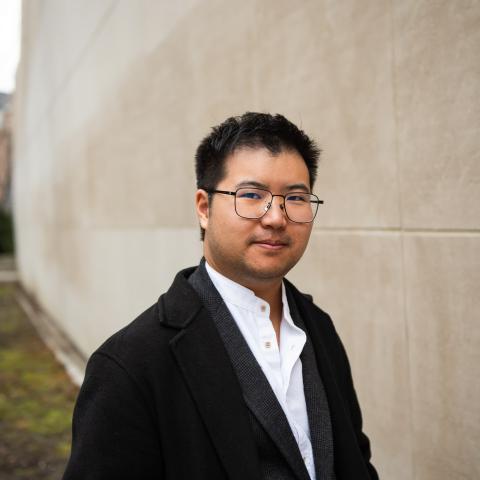 Man in black suit with eye glasses looking directly at the camera