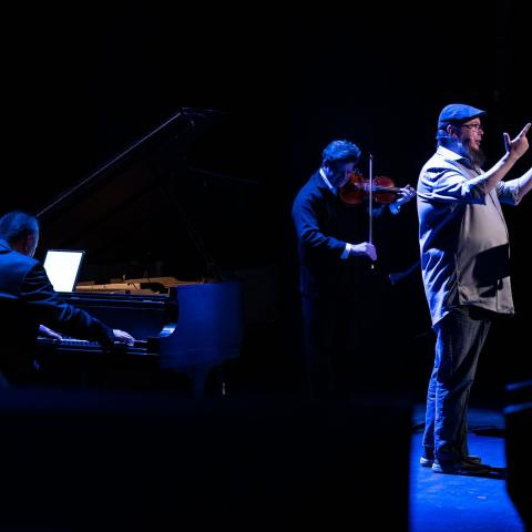 Shane stands on the stage with Barry Shiffman playing violin and Jon Kimura Parker playing piano