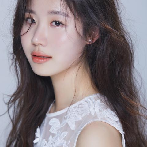 Woman with long dark hair and white shirt looking at camera
