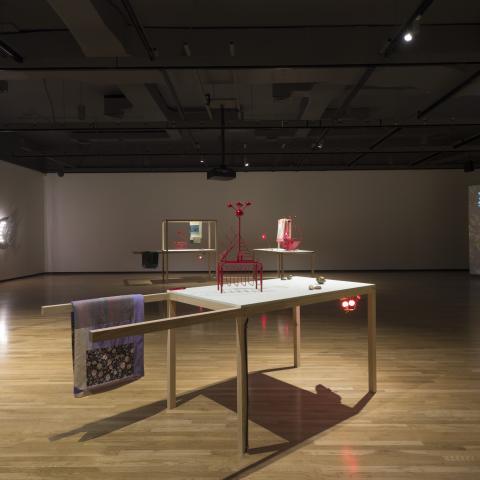 Desk with small abstract sculptures in middle of large room.