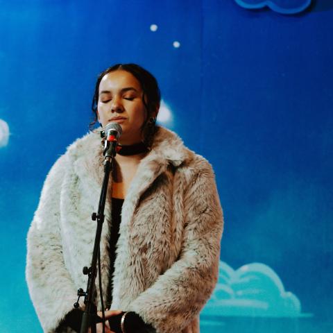 Women in fur coat performing in front of a microphone 