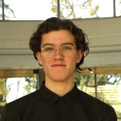 Man wearing black shirt and glasses looking at camera