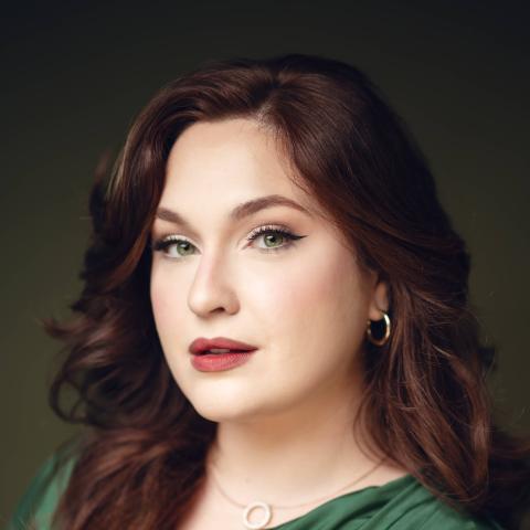 Woman in bright green shirt with red hair staring directly at camera