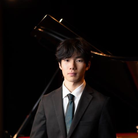 Man in black suit with blue tie and white collared shirt looking at camera