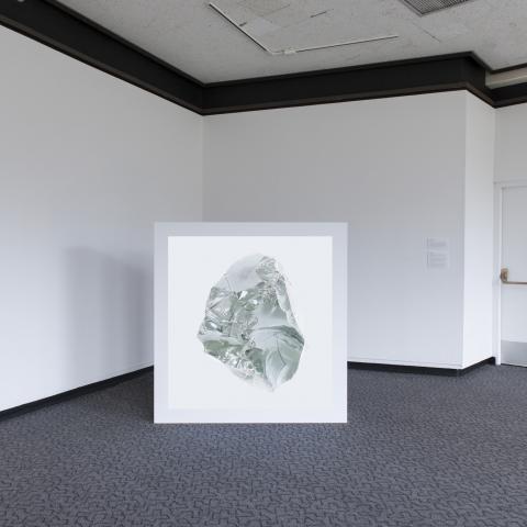 A white light box with an image of a rock sits in the corner of the room.