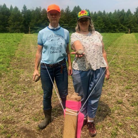 Deirdre Logue and Allyson Mitchell stand at the apex of a marked grass field