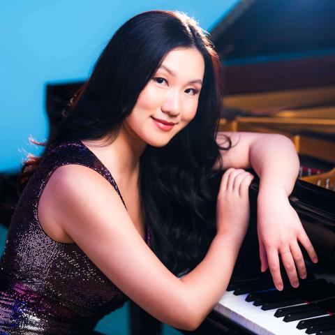 Woman Leaning over piano smiling at camera
