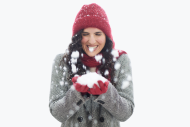 happy smiling Woman with winter red har and gloves holding ball of fresh snow between her hands 
