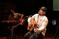 singer playing guitar on a stage 