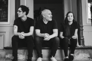 black and white picture of 3 persons seating on stairs wearing simple clothes